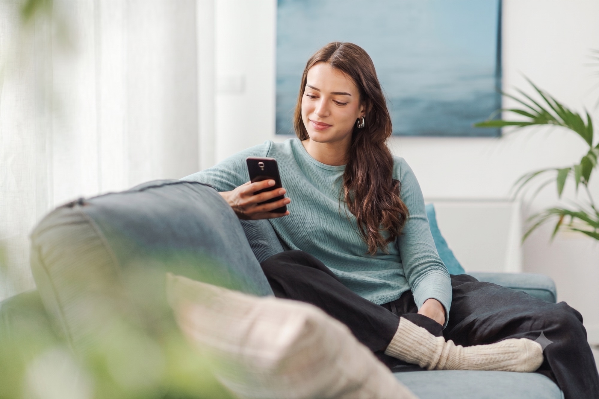 A resident on her sofa, checking her suite on her phone.